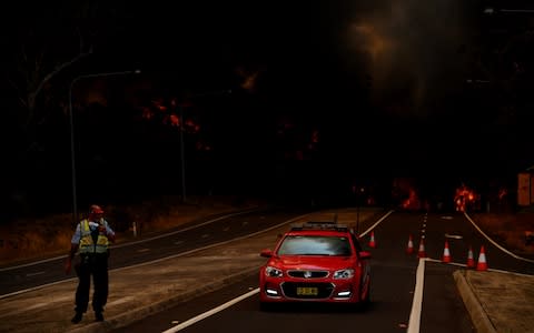 A police officer prepares to flee his roadblock in Sydney as the fire races towards him - Credit: SAM MOOY/GETTY IMAGES