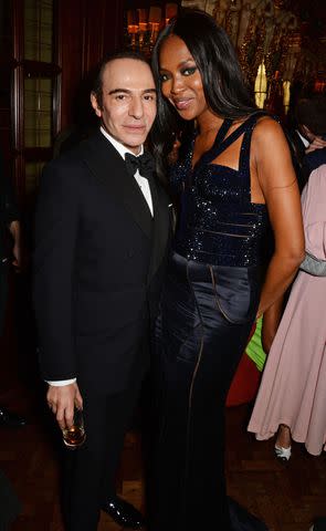 <p>David M. Benett/Getty</p> John Galliano and Naomi Campbell attend a party in celebration of Edward Enninful in London on December 1, 2014