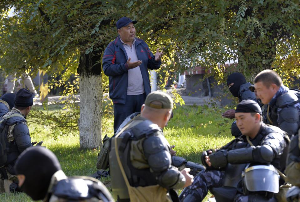 A man speaks to Kyrgyz police soldiers on a street in Bishkek, Kyrgyzstan, Thursday, Oct. 15, 2020. Kyrgyzstan President Sooronbai Jeenbekov announced his resignation on Thursday in a bid to end the turmoil that has engulfed the Central Asian nation after a disputed parliamentary election. (AP Photo/Vladimir Voronin)