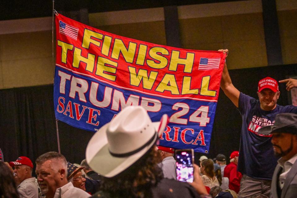 PHOTO: Supporters of former U.S. president and 2024 Republican presidential hopeful Donald Trump hold a sign about the border wall with Mexico before Trump speaks at a campaign rally at Club 47 USA, Oct. 11, 2023, in West Palm Beach, Fla. (Giorgio Viera/AFP via Getty Images, FILE)