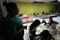 Iracema Figueroa, left, of Honduras, looks on as her children play with others at a shelter for migrants Friday, May 20, 2022, in Tijuana, Mexico. Figueroa has spent two years trying to reach a safe place for her family and was praying the judge would lift the order. Figueroa left Honduras in 2019 after gangs killed her uncle and threatened her three sons. (AP Photo/Gregory Bull)