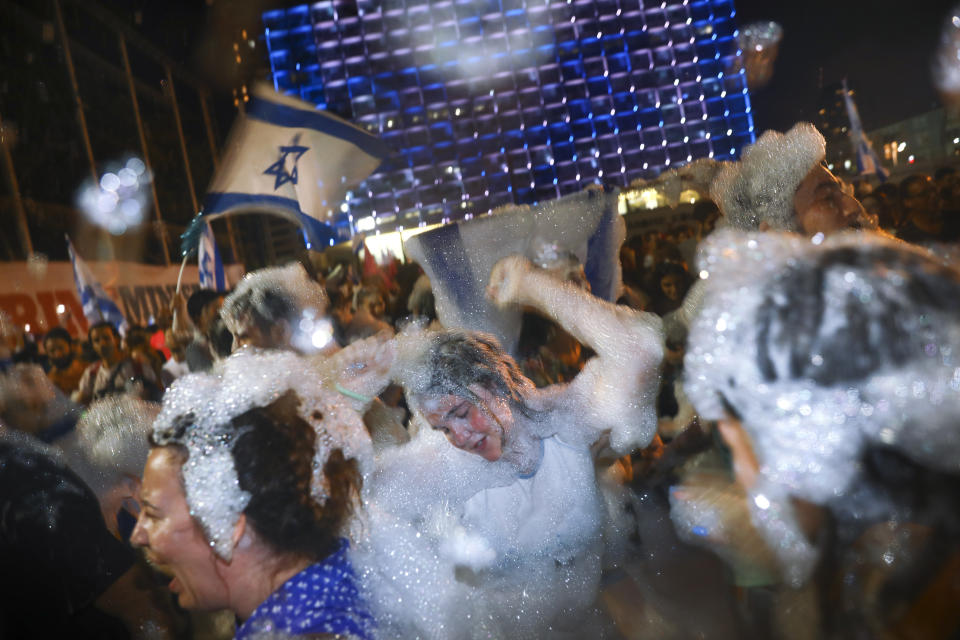 Israelis celebrate the swearing in of the new government in Tel Aviv, Israel, Sunday, June 13, 2021. Israel's parliament has voted in favor of a new coalition government, formally ending Prime Minister Benjamin Netanyahu's historic 12-year rule. Naftali Bennett, a former ally of Netanyahu became the new prime minister. (AP Photo/Oded Balilty)