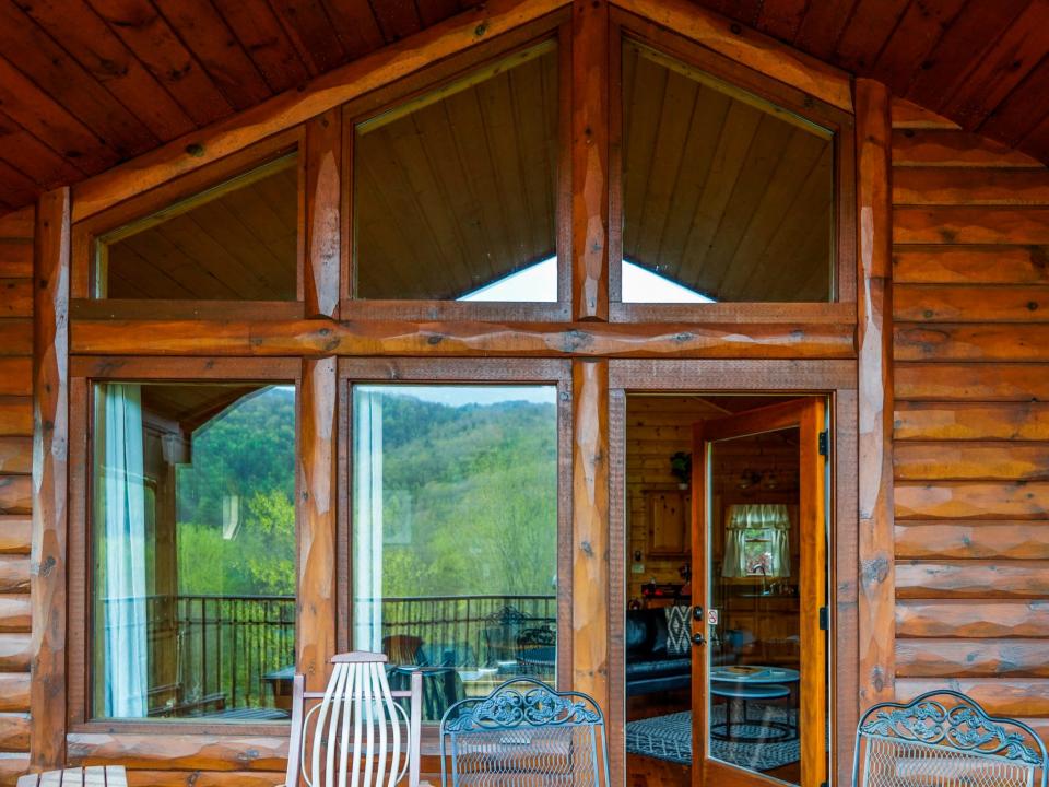 A view of the balcony shows the cabin's red-brown facade and wide windows