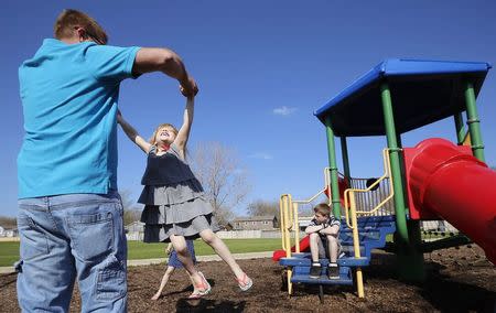 Joe Smith plays with his daughter Norah as his son Chase looks on at a playground in Winthrop Harbor, Illinois, May 9, 2014. REUTERS/Jim Young