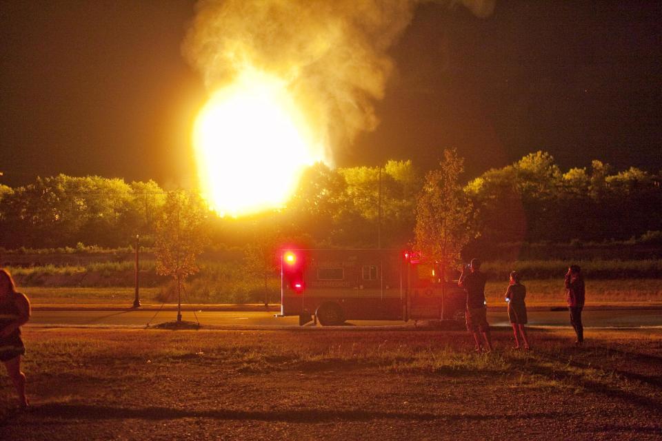 People watch the flames shoot up from a freight train that derailed and some cars burst into flames, early Wednesday morning July 11, 2012 in Columbus Ohio. Lt. Terry Bush says the accident happened at about 2 a.m. Wednesday in a mixed-use part of the city, and people living in one-mile radius of the blast have been evacuated. (AP Photo/Andrew Spear)