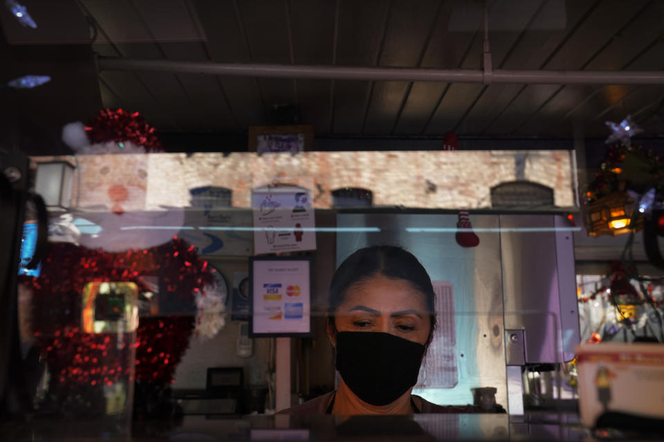 Debbie Briano, a fourth-generation owner of Mexican restaurant, El Rancho Grande, works in her restaurant on Olvera Street in downtown Los Angeles, Wednesday, Dec. 16, 2020. Briano still decorated her cafe like she normally would at Christmas. She bought poinsettias, put up a real tree, hung tinsel, lights, and strung little snowmen and Santa Claus above her window. "I had to do that to feel normal," she said. "I' m not going to let COVID take away our Christmas magic." (AP Photo/Jae C. Hong)