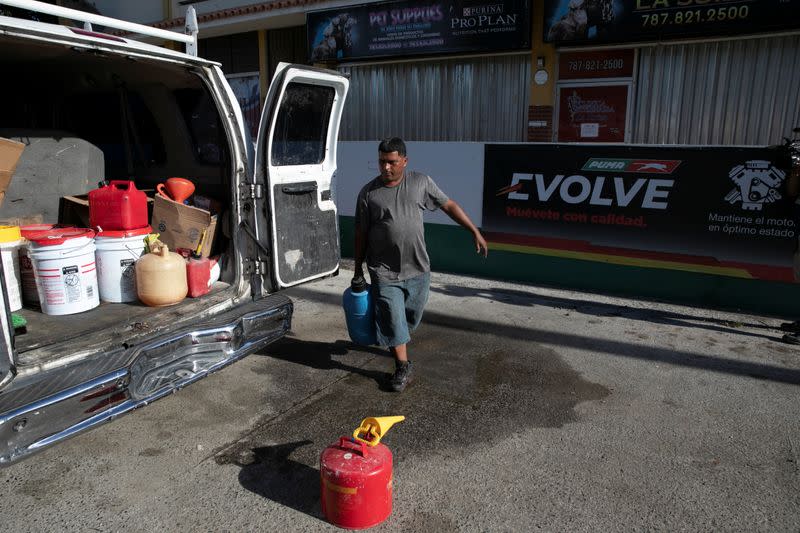 A man carries containers with fuel at a gas station after an earthquake in Guanica