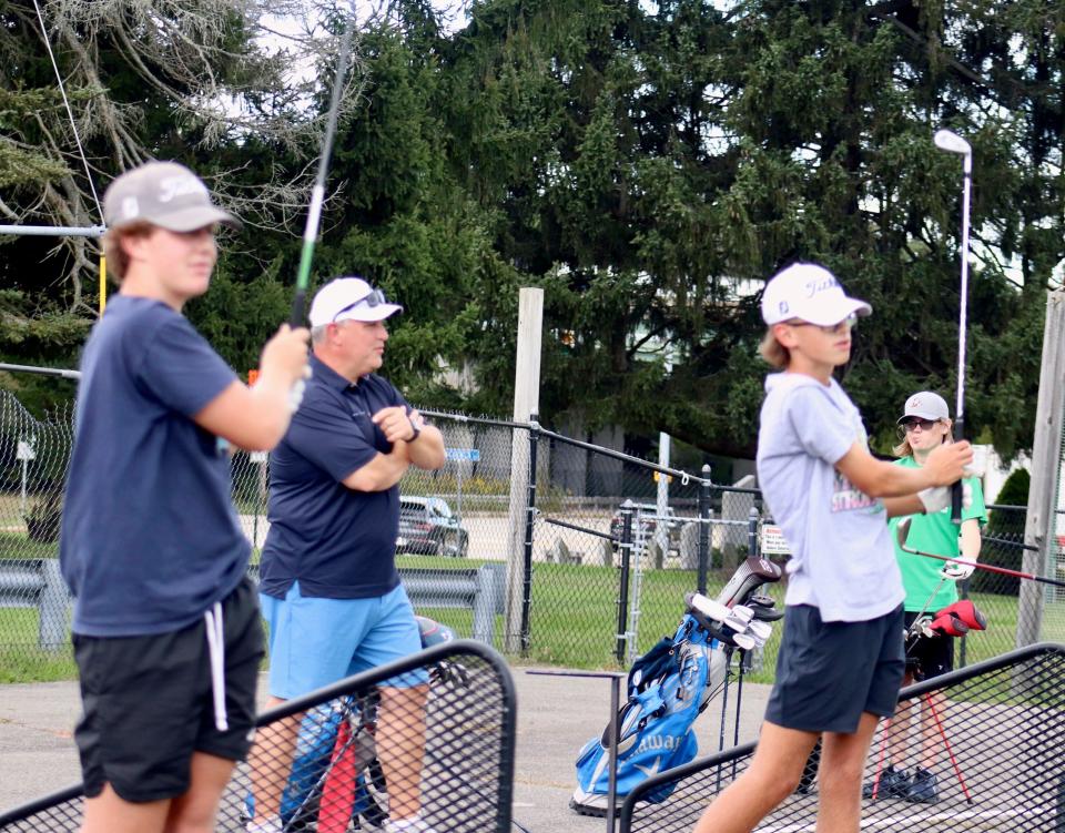 Auburn coach Dave Stanick guides two of his players Jon Rocheford, left, and Trevor Amero, right, at the Auburn Driving Range last week.