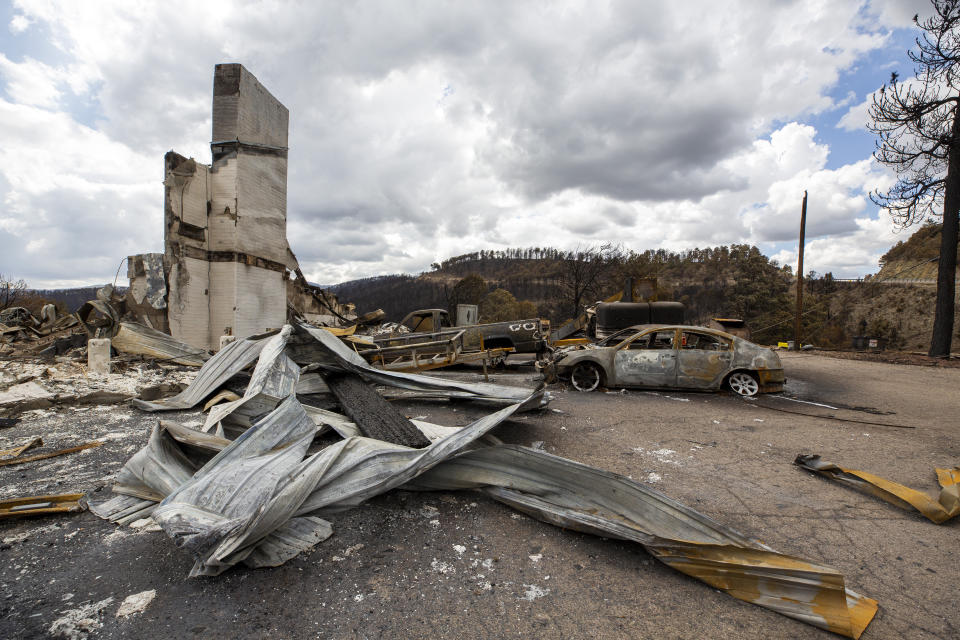 Charred vehicles and debris cover the parking lot of the Swiss Chalet Hotel after it was destroyed by the South Fork Fire in the mountain village of Ruidoso, N.M., Saturday, June 22, 2024. (AP Photo/Andres Leighton)