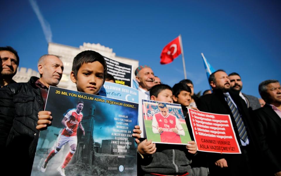 Ethnic Uighur boys hold placards with the pictures of English soccer club Arsenal's midfielder Mesut Ozil during a protest against China in Istanbul, Turkey December 14, 2019. The placard reads: 