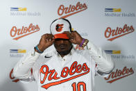 Former Baltimore Orioles player Adam Jones puts on a team cap during a news conference in which he signed a contract to officially retire prior to a baseball game between the Orioles and the Tampa Bay Rays, Friday, Sept. 15, 2023, in Baltimore. (AP Photo/Julio Cortez)