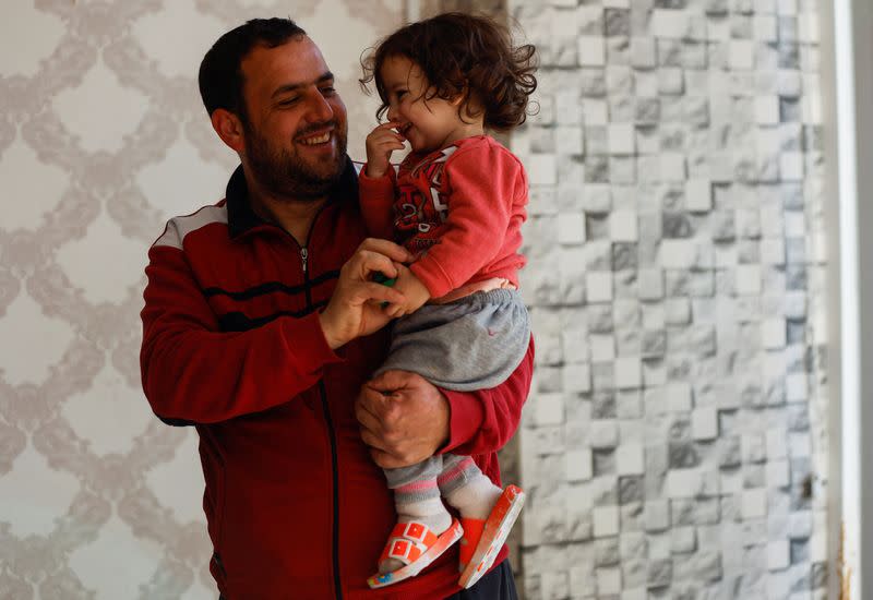 Bilal el-Sheikh, a displaced Syrian, holds his daughter at a makeshift shelter in Mersin