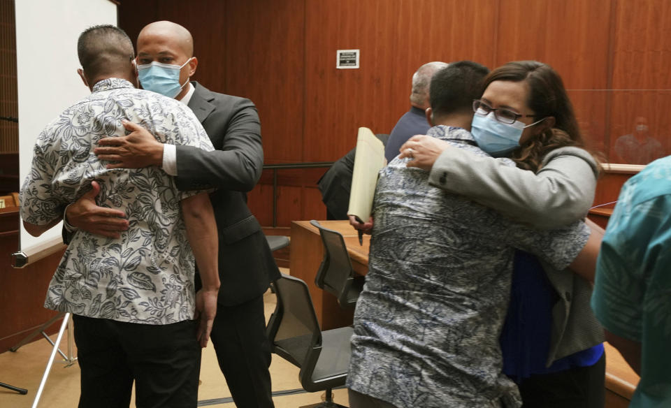 Defense attorney Thomas Otake, left facing camera, embraces Geoffrey Thom, as defense attorney Crystal Glendon, right facing camera, embraces her client Christopher Fredeluces after Judge William Domingo rejected murder and attempted murder charges against the officers in the fatal shooting of a teenager, preventing the case from going to trial, Wednesday, Aug. 18, 2021, at district court in Honolulu. (Cory Lum/Honolulu Civil Beat via AP, Pool)