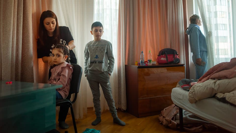 Narine with her children Nicole (6) and Valentine (9). The family were preparing to leave Regina Pacis, Moldova, with their friend Yuliia looking out for a minibus that will drive them to Italy. March 2022. - Courtesy Polly Braden