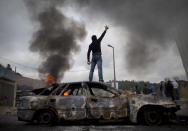 <p>A Palestinian demonstrator stands on a burned-out car during clashes with Israeli troops following a demonstration to mark the 63rd anniversary of “Nakba” — Arabic for “Catastrophe”— in the east Jerusalem neighborhood of Issawiyeh, May 15, 2011. (Photo: Oded Balilty/AP) </p>