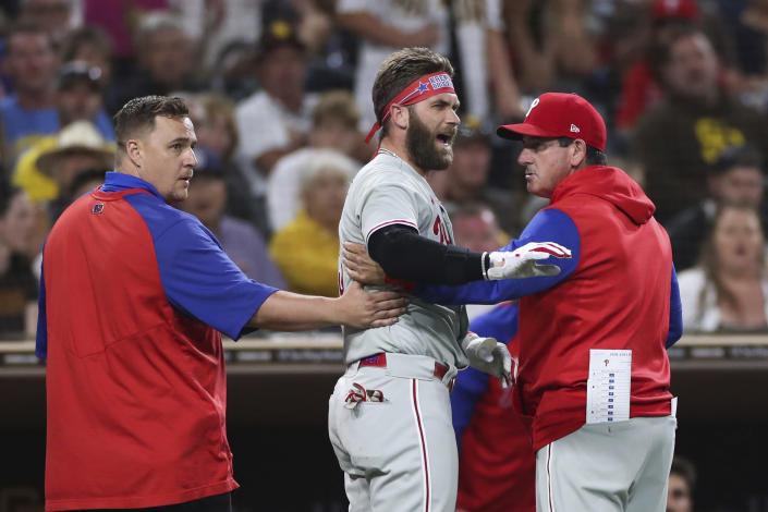 Philadelphia Phillies' Bryce Harper, center, reacts towards San Diego Padres pitcher Blake Snell after being hit by a pitch, as he walks off the field with interim manager Rob Thomson, right, and a trainer during the fourth inning of a baseball game Saturday, June 25, 2022, in San Diego. (AP Photo/Derrick Tuskan)
