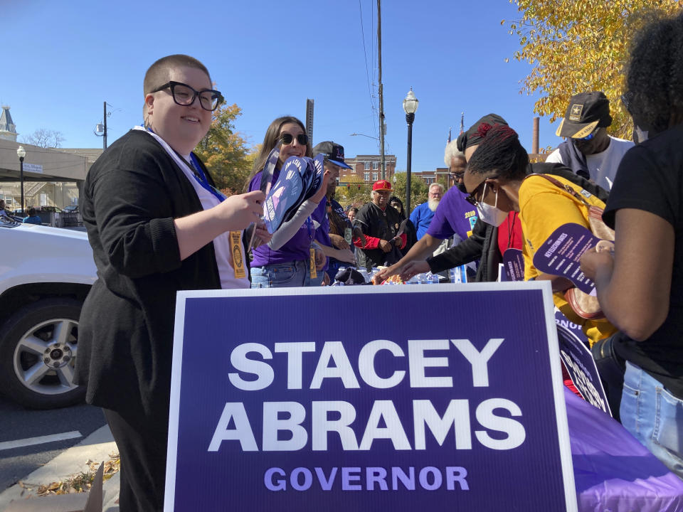 Campaign workers hand out fans, t-shirts and buttons to supporters of Democratic governor candidate Stacey Abrams on Thursday, Oct. 27, 2022, in Milledgeville, Ga. Georgia's top candidates are making appeals to their partisan bases as early voting continues in the state ahead of the Nov. 8 general election. (AP Photo/Jeff Amy)