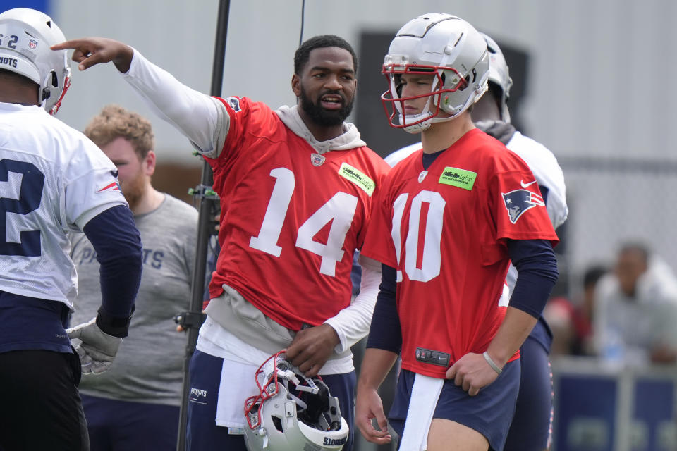 New England Patriots quarterback Jacoby Brissett (14) speaks with quarterback Drake Maye (10) during an NFL football practice, Monday, May 20, 2024, in Foxborough, Mass. (AP Photo/Steven Senne)