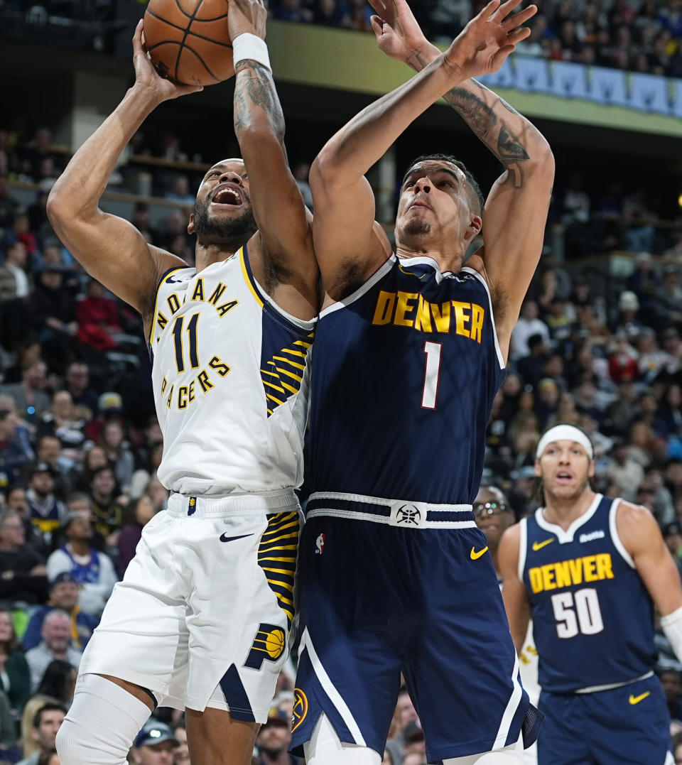 Indiana Pacers forward Bruce Brown, left, drives to the basket as Denver Nuggets forward Michael Porter Jr. defends in the first half of an NBA basketball game, Sunday, Jan. 14, 2024, in Denver. (AP Photo/David Zalubowski)