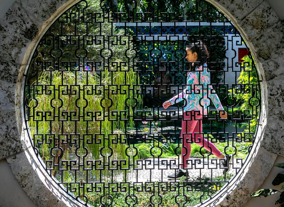 A woman makes her way through the Chinese Demonstration Garden at the Society of the Four Arts Friday, February 23, 2024.