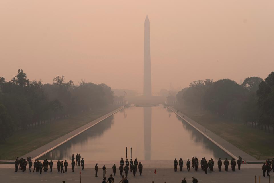 With smoke from hundreds of miles north clouding the scene, the Marine Corps honor color guard rehearses on Thursday with the Washington Monument in the background in Washington, D.C. Canadian wildfires are blanketing the northeastern United States in a dystopian haze that reaches into parts of mid-Atlantic and even Southern states.