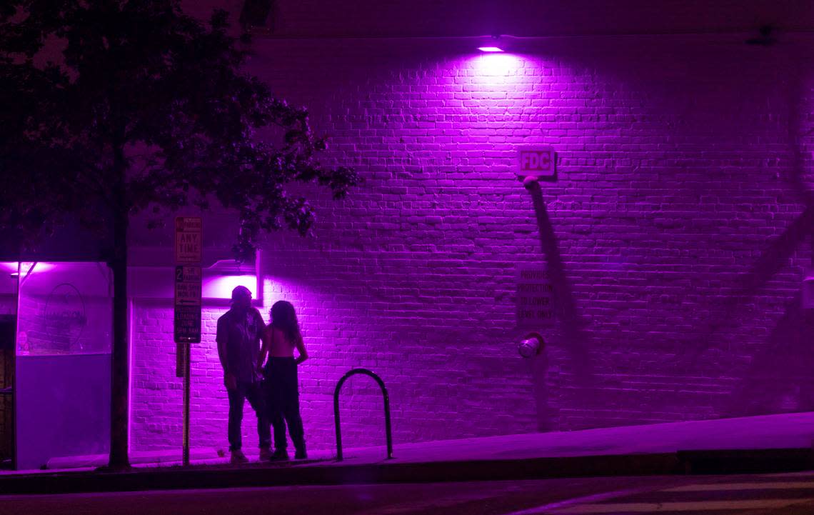 A couple talks beneath the purple glow of lights along Jones Street near Halcyon Bar + Lounge on Friday July 21, 2023 in Raleigh, N.C.