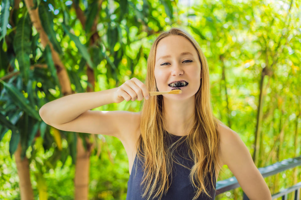 person brushes their teeth with charcoal floss