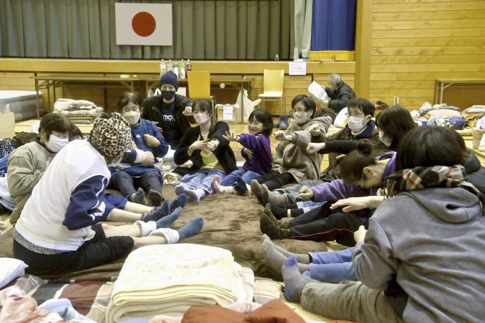 Local residents in the quake-hit area, stretch out together at a shelter in Anamizu, Ishikawa prefecture, Sunday, Jan. 7, 2024. Rescue teams worked through snow to deliver supplies to isolated hamlets Monday, a week after a powerful earthquake hit western Japan. (Kyodo News via AP)