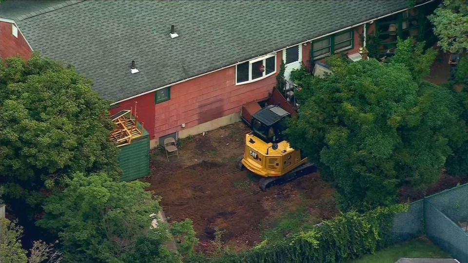 PHOTO: Heavy equipment sits in the backyard as investigators comb through the home of Rex Heuermann in Massapequa Park, N.Y. after he was arrested as a suspect in the Gilgo Beach killings, July 24, 2023. (WABC)