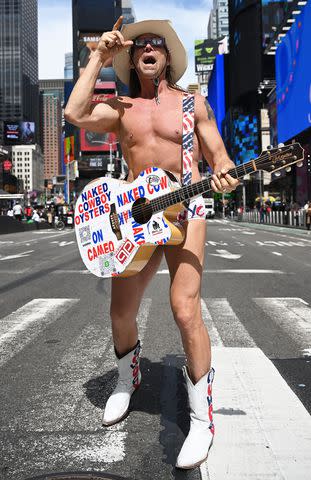 <p>Erik Pendzich/Shutterstock </p> The Naked Cowboy watches the eclipse