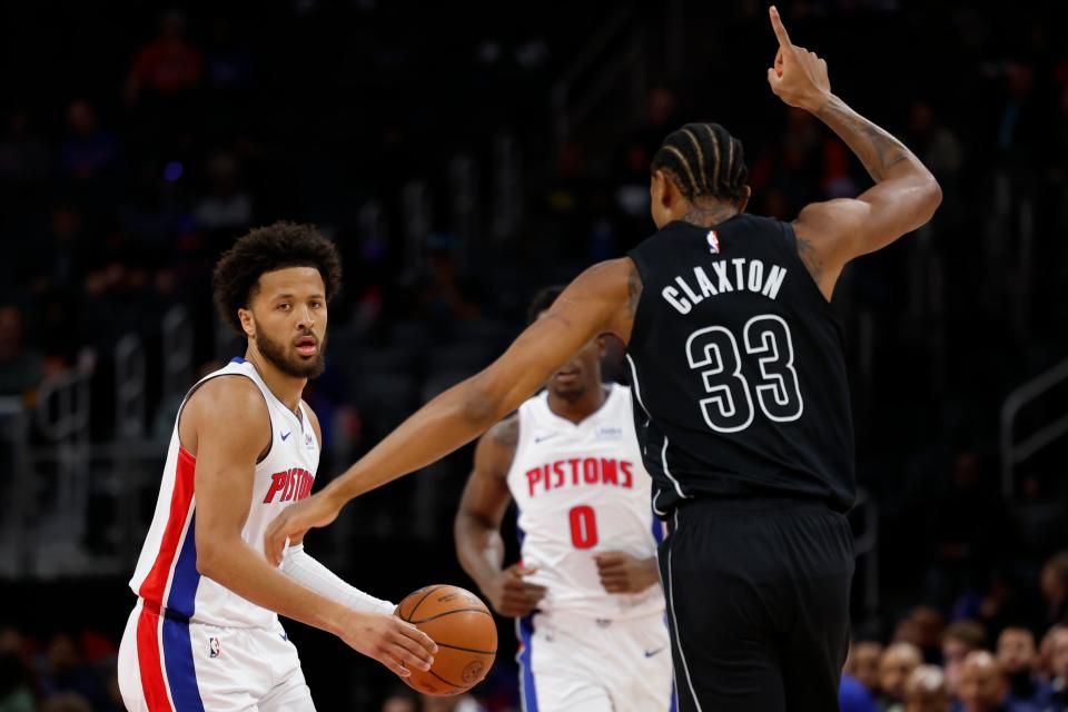Detroit Pistons guard Cade Cunningham (2) dribbles defended by Brooklyn Nets center Nic Claxton (33) in the first half at Little Caesars Arena in Detroit on Thursday, March 7, 2024.