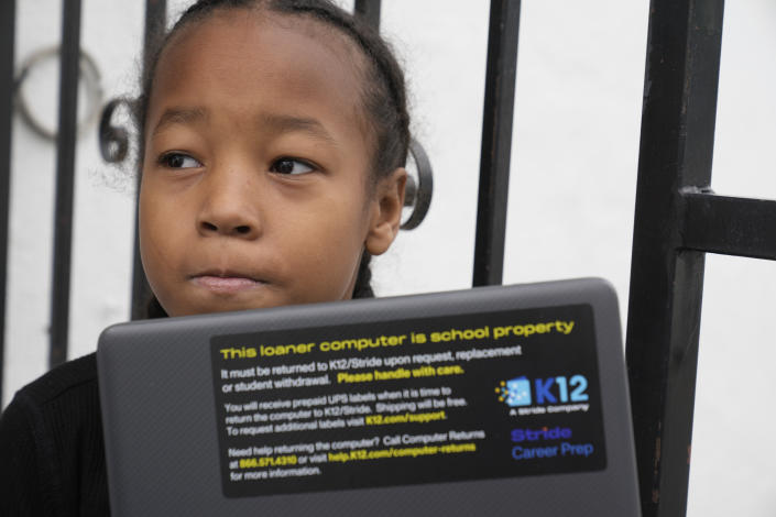 Ezekiel West, 10, opens up his K12/Stride school loaner laptop computer outside his home in Los Angeles on Sunday, Jan. 15, 2023. In January, Ezekiel began studying in a public online school for California students, but his mother and attorney are concerned the program isn't flexible enough for Ezekiel, who is years behind in reading. (AP Photo/Damian Dovarganes)