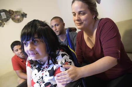 Alma Rivera, 39, watches television in her chair with her nephew Gabriel Baez, 14, brother-in-law Isuain Luna and sister Nathalie Rivera (R) at their home in Kissimmee, Florida, U.S. December 2, 2016. REUTERS/Phelan Ebenhack