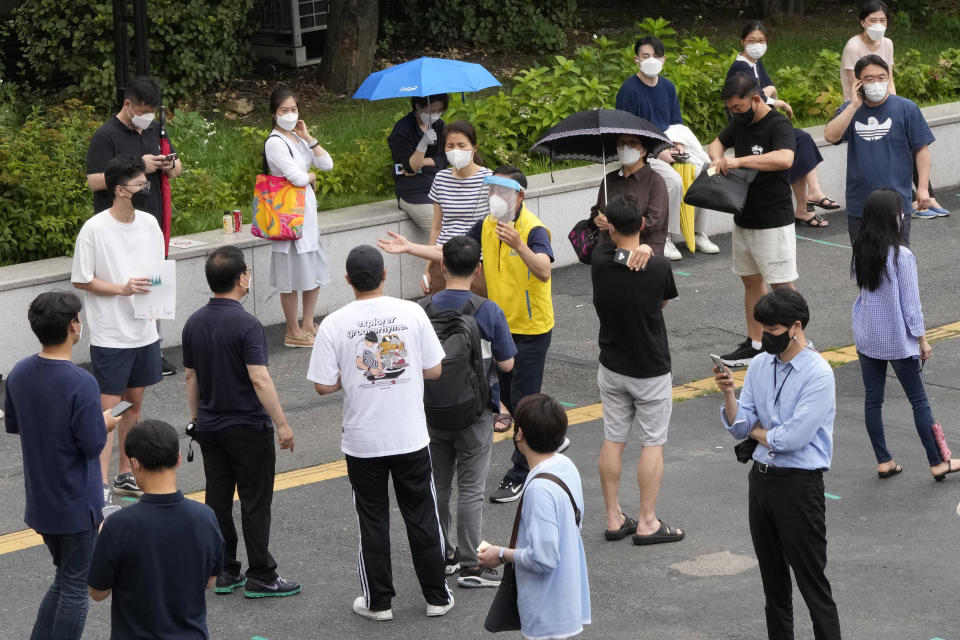 A government official, center, wearing a face mask and shield explains about the coronavirus testing to people at a coronavirus testing site in Seoul, South Korea, Friday, July 9, 2021. South Korea will enforce its strongest social distancing restrictions in the greater capital area starting next week as it wrestles with what appears to be the worst wave of the coronavirus since the start of the pandemic. (AP Photo/Ahn Young-joon)