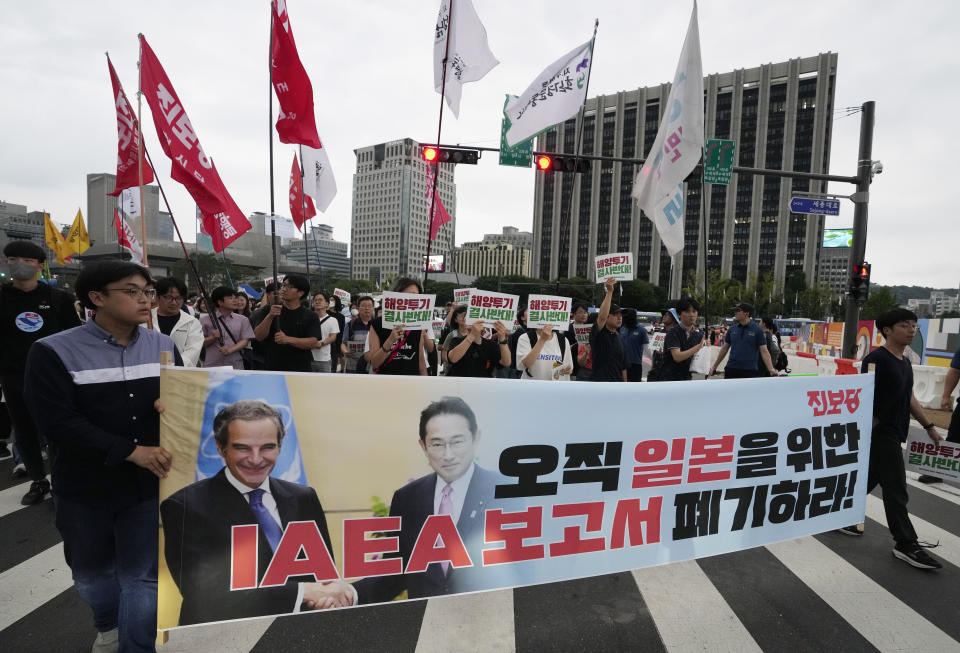 Protesters with a banner showing an image of Rafael Mariano Grossi, Director General of the International Atomic Energy Agency, left, and Japanese Prime Minister Fumio Kishida march toward the Japaneses Embassy during a rally against the Japanese government's decision to release treated radioactive water from the damaged Fukushima nuclear power plant, in Seoul, South Korea, Saturday, July 8, 2023. The letters read, "Discard the IAEA report." (AP Photo/Ahn Young-joon)