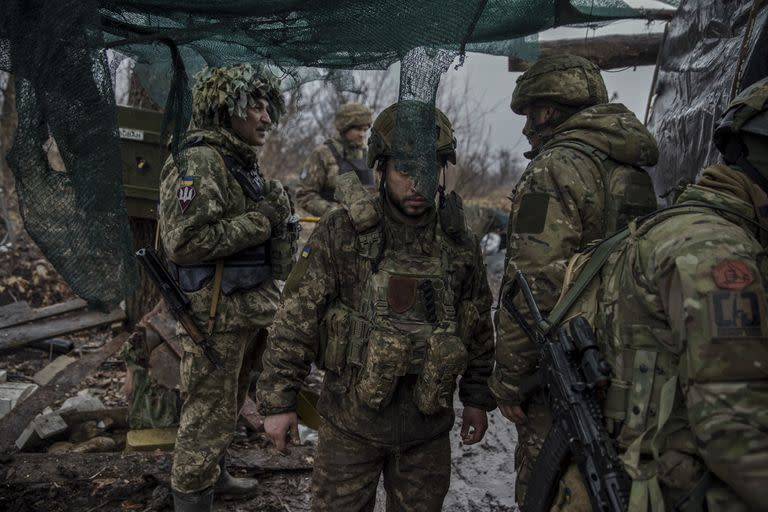Miembros de la 79ª Brigada de Asalto Aéreo en una trinchera en una zona de Marinka, en el este de Ucrania, el 26 de febrero de 2023. Se colocan redes y zarzas para ocultar sus contornos a los atacantes.