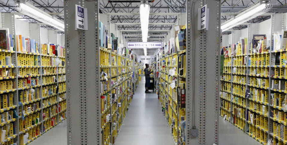 FILE - In this Monday, Dec. 2, 2013, file photo, an Amazon.com employee stocks books at the Amazon.com Fulfillment Center in Phoenix. Holiday sales jobs are now likelier to be in warehouses and trucks than in retail stores. Amazon alone planned to hire 20,000 more holiday workers this year, according to the personnel firm Challenger, Gray & Christmas. (AP Photo/Ross D. Franklin, File)