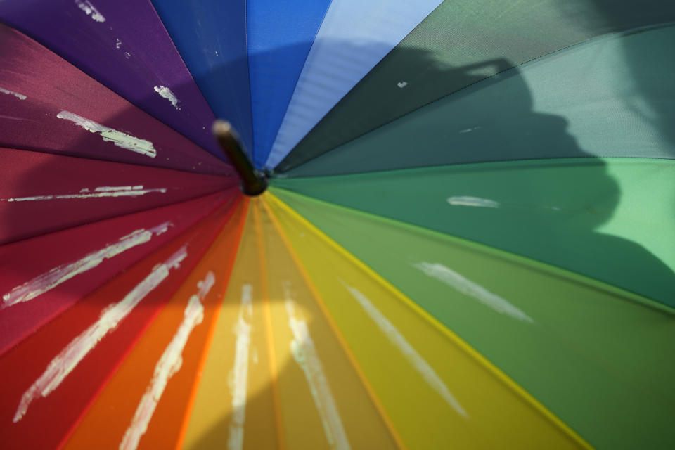 A demonstrator casts a shadow on a rainbow colored umbrella during a march to celebrate International Transgender Day of Visibility in Lisbon, March 31, 2023. Sunday, March 31, 2024 is International Transgender Day of Visibility, a day full of events around the world to bring attention to a population that's often ignored or disparaged or victimized. (AP Photo/Armando Franca, file)