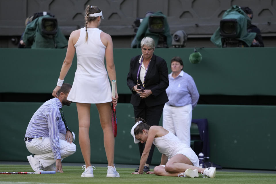 Match officials and Kazakhstan's Elena Rybakina check on the condition of Alize Cornet of France after she slipped and fell in a women's singles match on day four of the Wimbledon tennis championships in London, Thursday, July 6, 2023. (AP Photo/Kirsty Wigglesworth)
