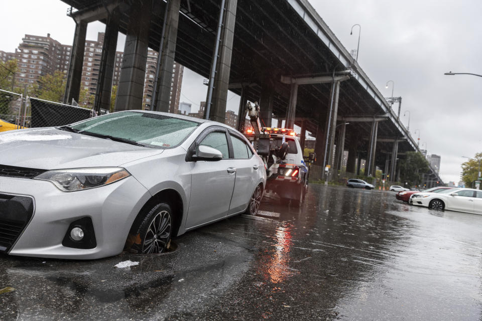 A car is towed away after getting stuck in a manhole cover during flash flooding near the FDR highway, underneath Williamsburg Bridge in the Lower East Side of Manhattan on Friday, Sept. 29, 2023 in New York. A potent rush-hour rainstorm swamped the New York metropolitan area on Friday, shutting down some subways and commuter railroads, flooding streets and highways, and delaying flights into LaGuardia Airport.(AP Photo/Stefan Jeremiah)