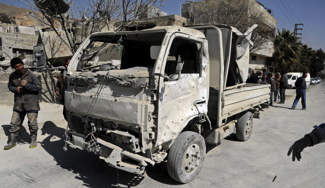 In this photo released by the Syrian official news agency SANA, people inspect damage after an Israeli airstrike near Damascus, Syria, Monday, March 7, 2022. Israel fired several missiles toward Syrian military positions near the capital Damascus Monday, killing two civilians and causing material damage, Syria's defense ministry said. It was the first Israeli attack inside Syria since Russia, a key backer of President Bashar Assad, invaded Ukraine. (SANA via AP)