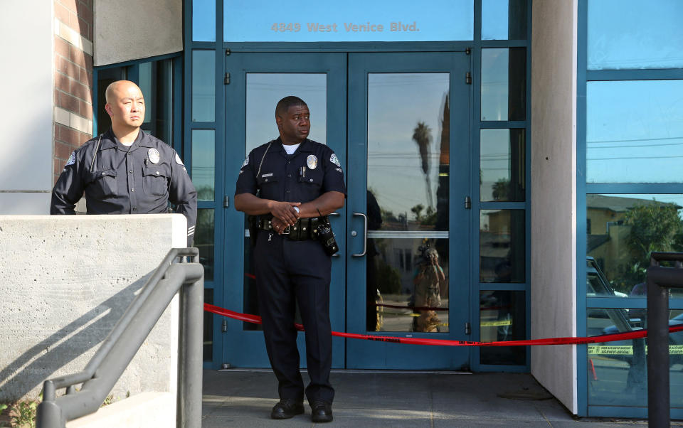 Los Angeles police officers stand outside the West Traffic Division station Tuesday, April 8, 2014, after an officer was shot and wounded inside the station Monday evening. A gunman who opened fire inside the police station, hitting one officer several times, was hospitalized early Tuesday in critical condition after he was wounded in the ensuing gunbattle, authorities said. (AP Photo/Nick Ut )