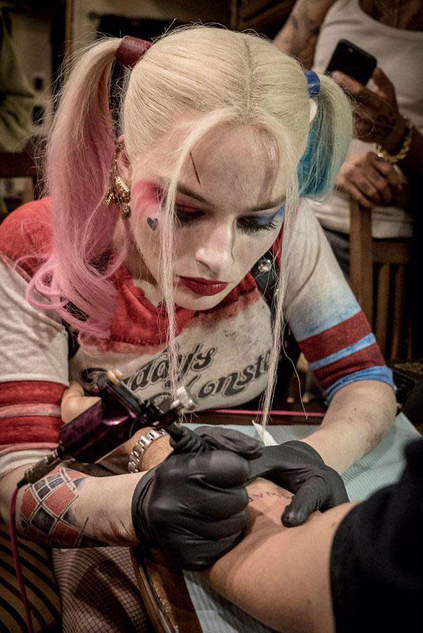 Margot Robbie in character as Harley Quinn using a tattoo gun.