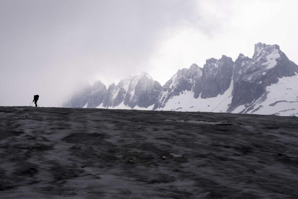 A cameraman walks up to the Rhone Glacier near Goms, Switzerland, Friday, June 16, 2023. (AP Photo/Matthias Schrader)