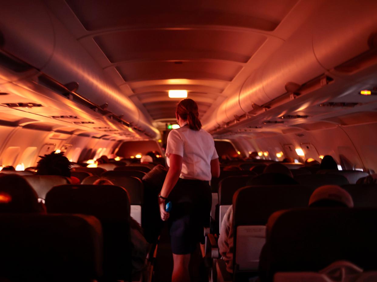 A flight attendant walks through an airplane before the plane's descent into the Dallas/Fort Worth International Airport on November 24, 2021 in Dallas, Texas.