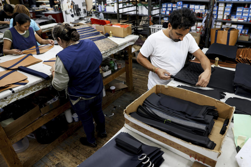 Alex Dabagh, right, assembles a pirarucu leather bag, Wednesday, Nov. 2, 2022, in New York. Park Avenue International, a family-owned leather goods factory in Manhattan's Garment District, produces Piper & Skye's handbags made from the discarded skin of the giant endangered pirarucu, a giant fish native to the Amazon in Brazil. (AP Photo/Julia Nikhinson)