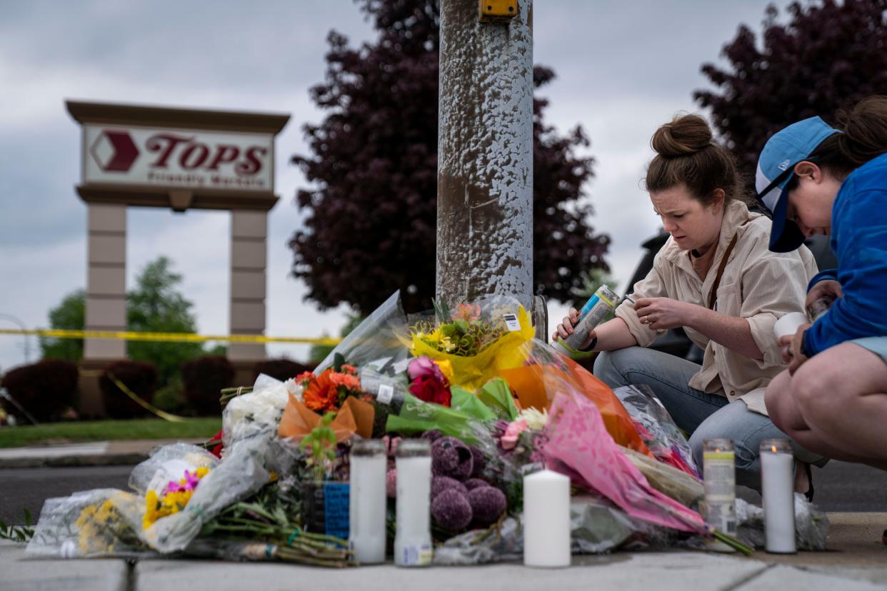 Carlee Taggart of Chicago and Robyn Harpell, of Virginia Beach light candles at a makeshift memorial near the scene of a mass shooting at Tops Friendly Market at Jefferson Avenue and Riley Street on Monday, May 16, 2022 in Buffalo, NY. The fatal shooting of 10 people at a grocery store in a historically Black neighborhood of Buffalo by a young white gunman is being investigated as a hate crime and an act of racially motivated violent extremism, according to federal officials.