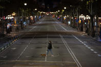 A resident walks with a dog on an empty street after curfew in Barcelona on Sunday, Oct. 25, 2020. Spain orders nationwide curfew to stem worsening outbreak. Spanish Prime Minister Pedro Sánchez has declared a second nationwide state of emergency in hopes of stemming a resurgence in coronavirus infections. (AP Photo/Emilio Morenatti)