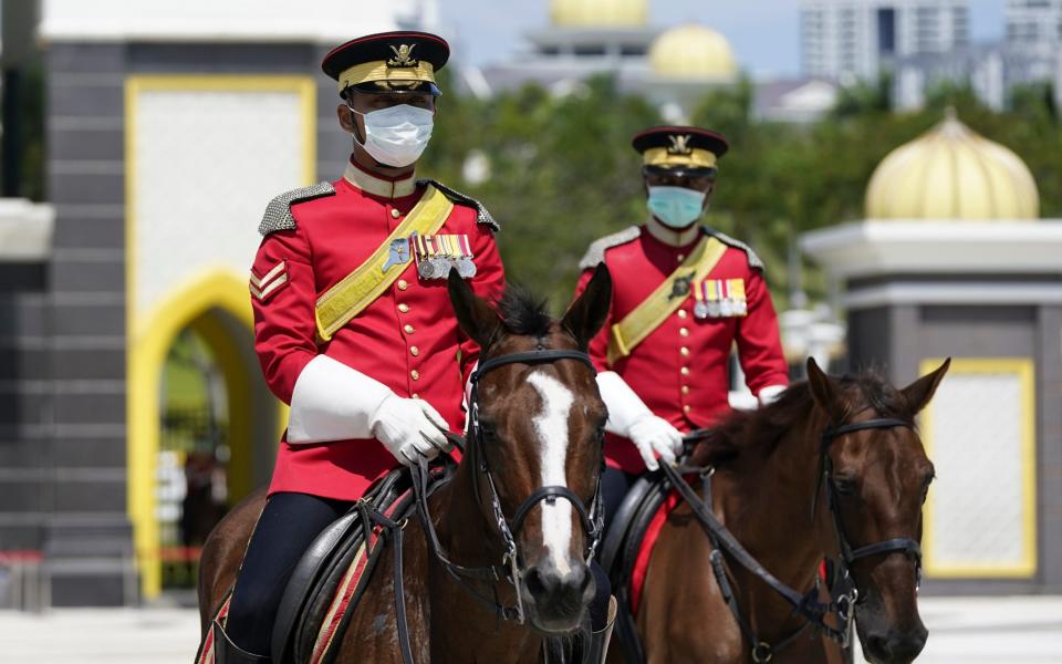 Honour guards wearing protective face masks patrol outside National Palace in Kuala Lumpur, Malaysia - Vincent Thian / AP