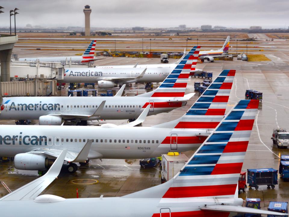 A number of American Airlines planes docked at an airport.